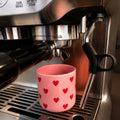Becher Herzen unter einer Espressomaschine