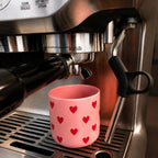 Becher Herzen unter einer Espressomaschine
