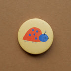 Button Marienkäfer auf braunem Grund