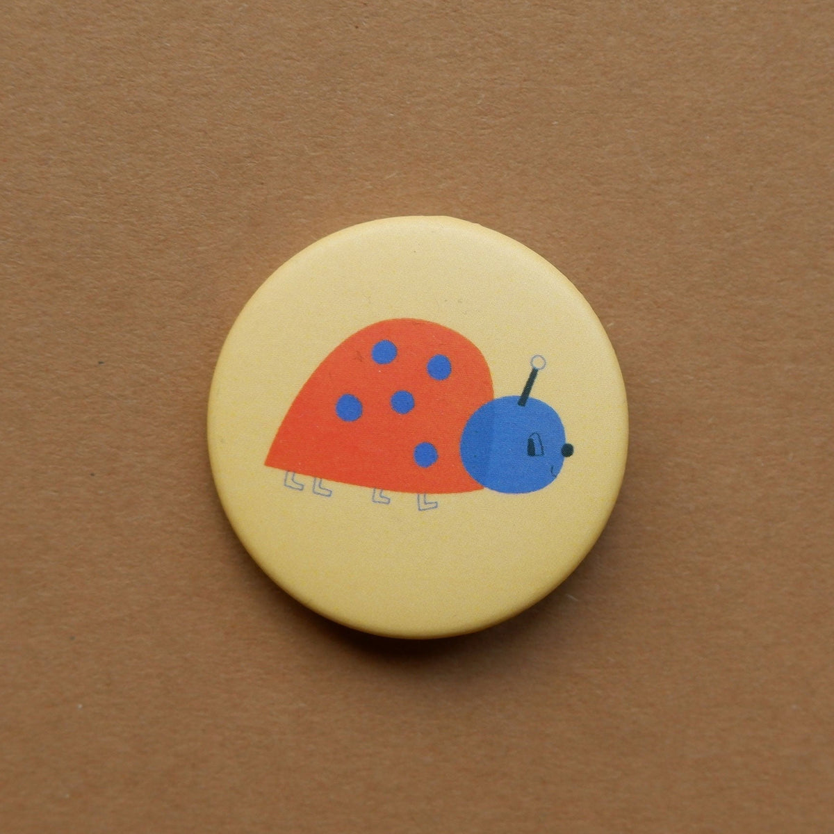Button Marienkäfer auf braunem Grund