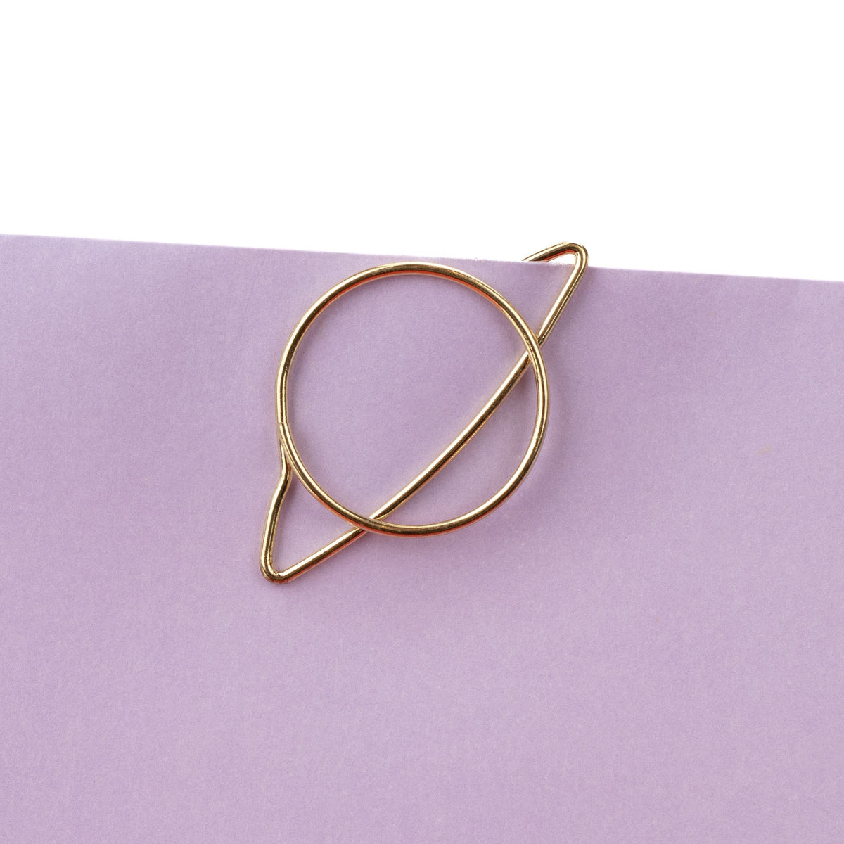 Goldener Clip in Saturnform an einem Papierrand
