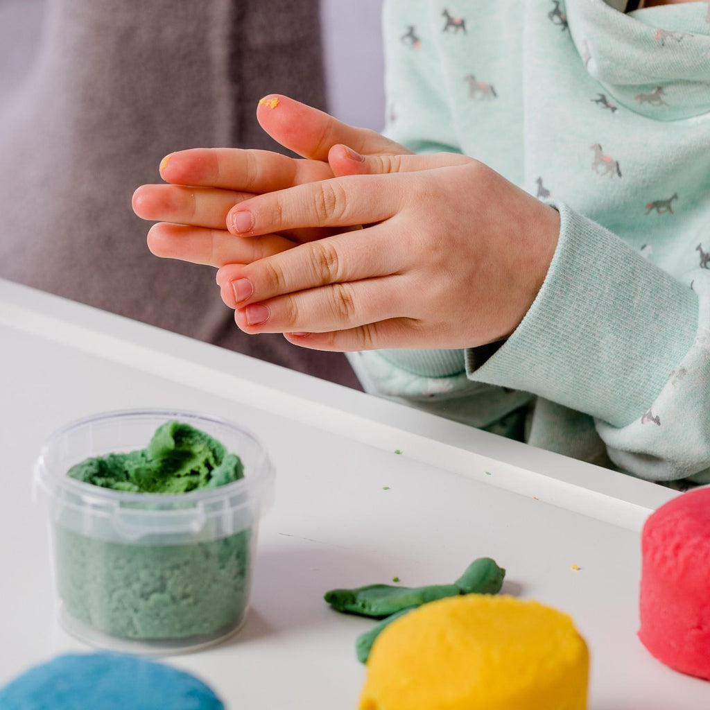 Kinderhände rollen Knete auf dem Tisch
