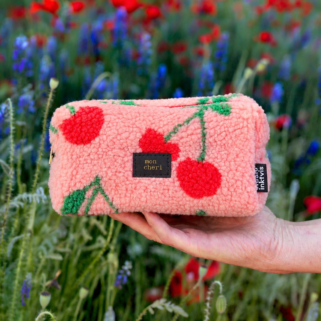 Rosa Teddy-Etui mit roten Kirschen in der Hand