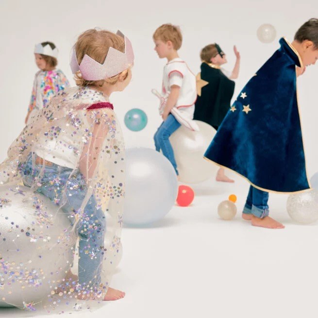 Kinder spielen in Umhängen mit Ballons