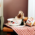 Schüssel und Tasse Happy mit Stoffmaus auf einem karierten Tuch