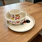 Kindertasse in der passenden Schüssel auf einem Teller