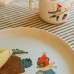 Kindertasse Waldtiere hinter einem Teller mit Dachs und Fuchs