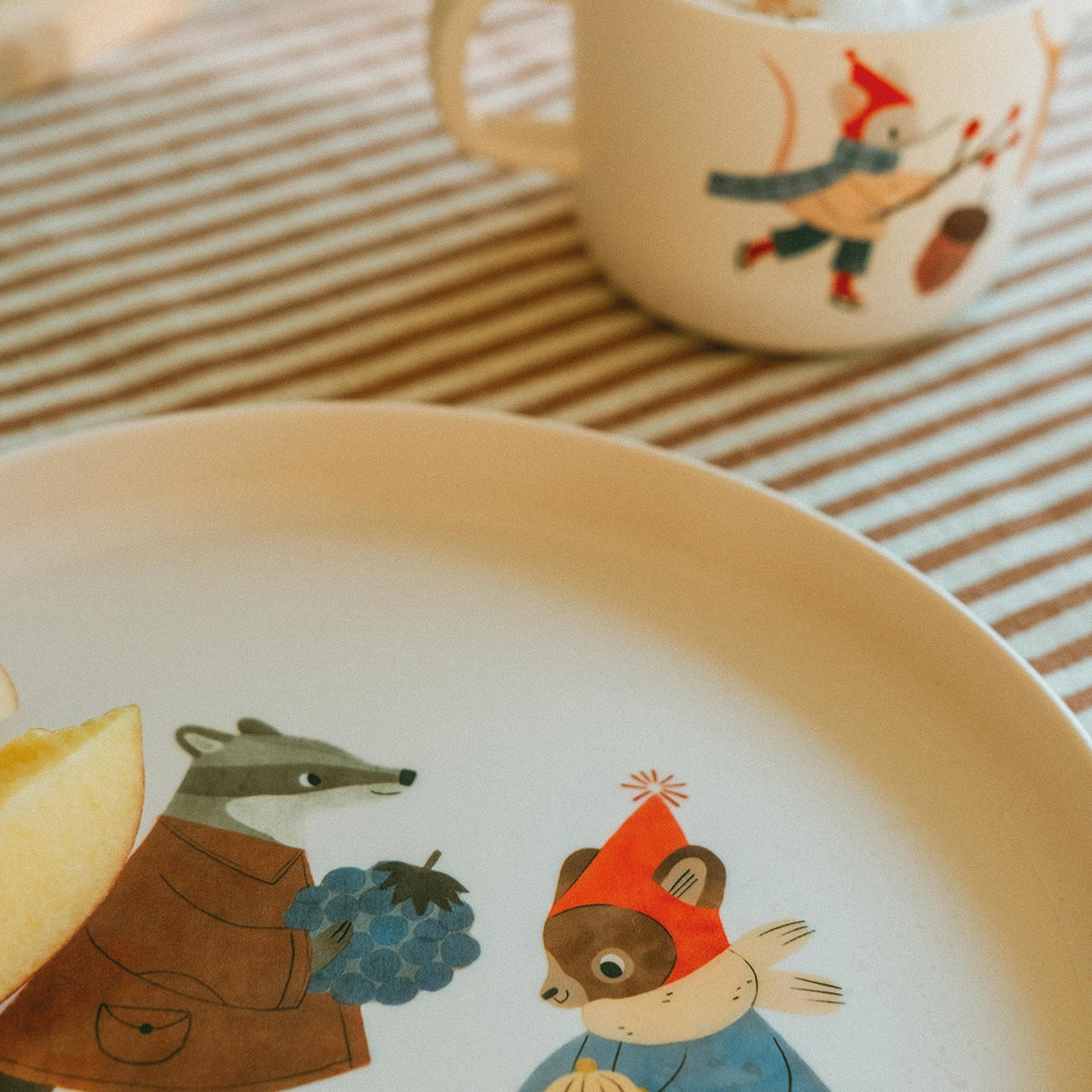 Kindertasse Waldtiere hinter einem Teller mit Dachs und Fuchs