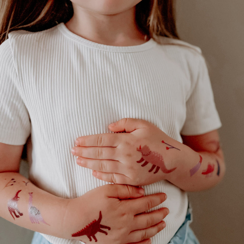 Kind mit Dino-Tattoos auf Armen und Händen