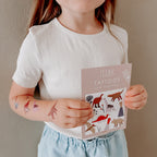 Kind mit Dino-Tattoos hält die Tattookarte