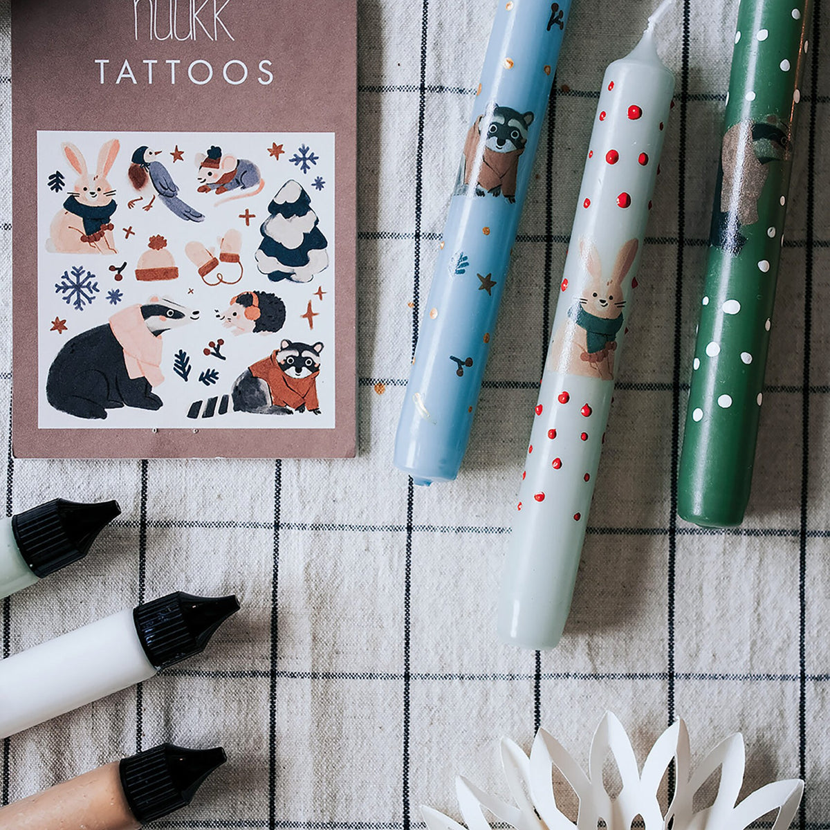 Tattookarte neben Kerzen, die mit Tiermotiven beklebt sind