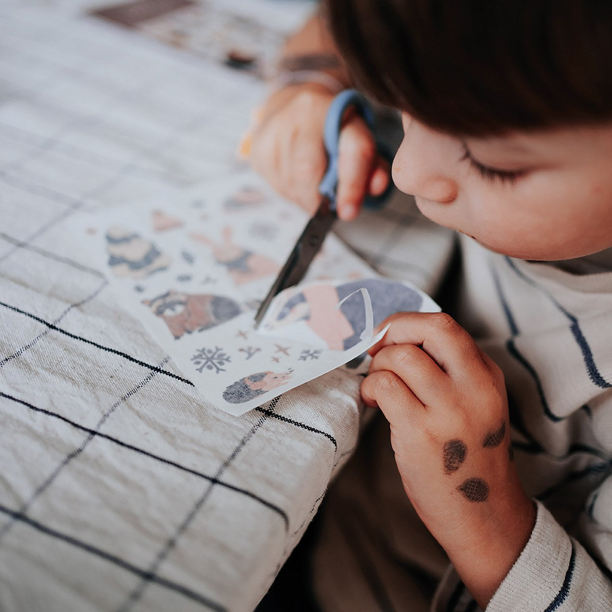 Kind schneidet ein Tattoo aus, auf dem Handrücken ein Dachs-Tattoo