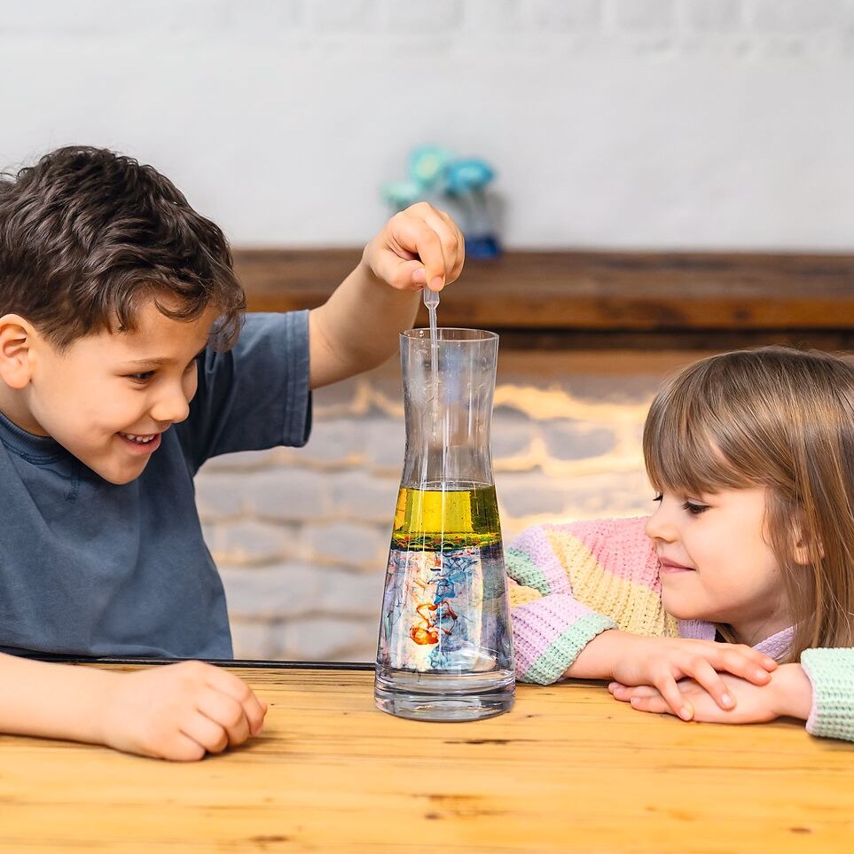 Zwei Kinder experimentieren mit einer Karaffe