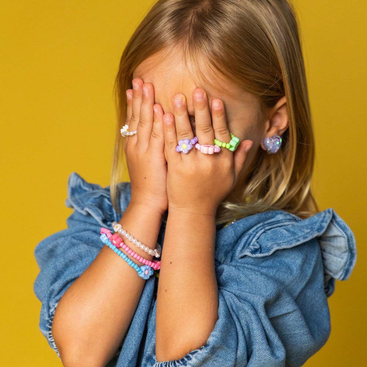 Mädchen hält die Hände mit Ringen vors Gesicht