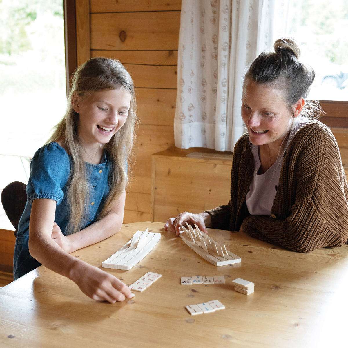 Zwei Mädchen spielen Rummy am Holztisch