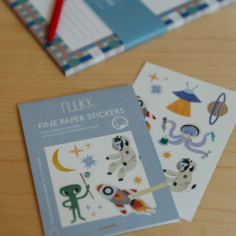 Stickerbogen Space neben dem Heft auf einem Holztisch