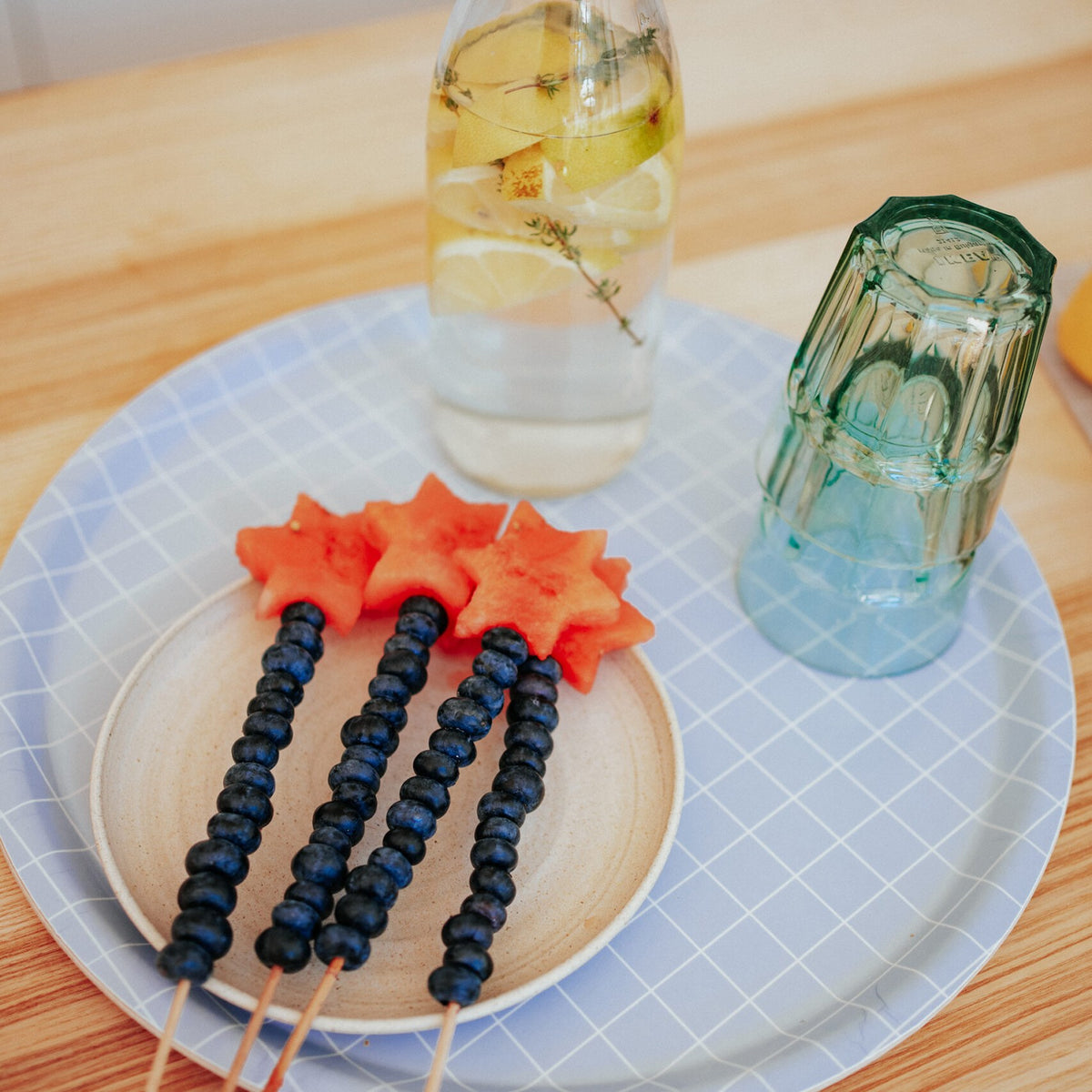 Tablett mit Melonensternen, Blaubeerspießen, Karaffe und Glas